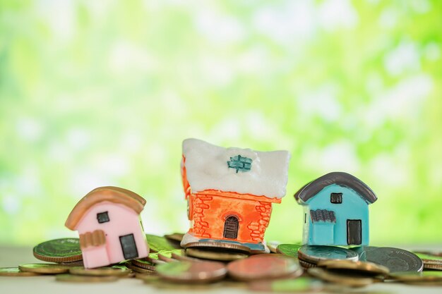 Mini house on pile of coins with green blur. 