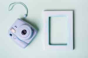 Foto gratuita mini macchina fotografica istantanea e cornice vuota bordo su sfondo blu