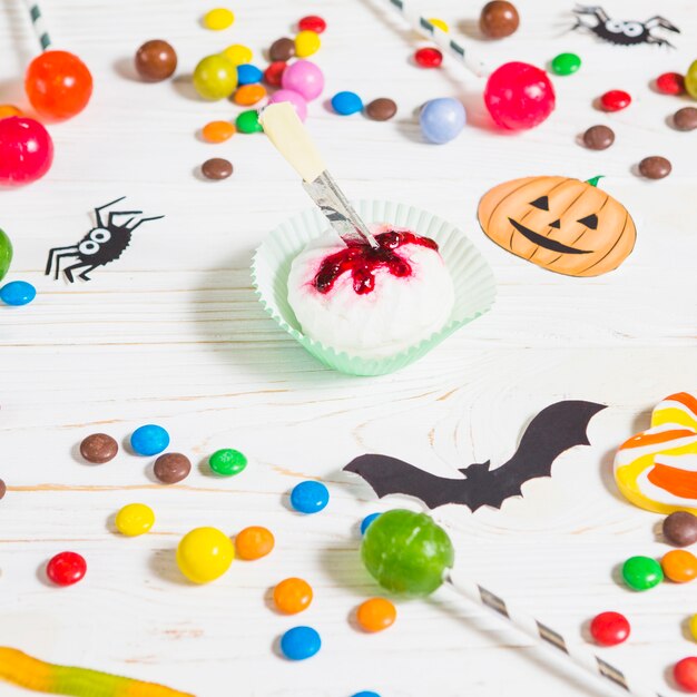 Mini muffin near little candies, bats, spiders and bonbon 