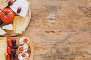 Foto gratuita mini panini con blocchi di formaggio e pomodori sullo scrittorio di legno