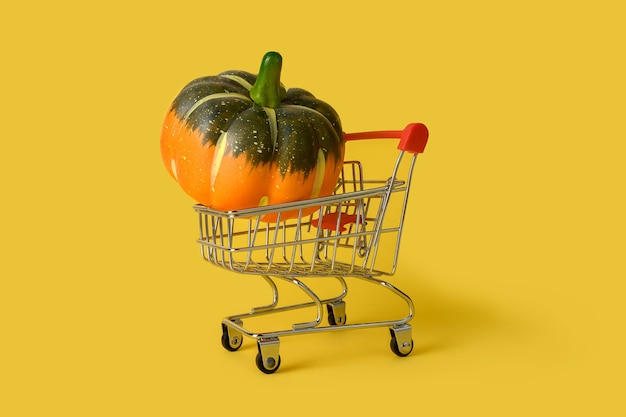 Mini shopping basket with pumpkin isolated on yellow background. retail. online sales concept.