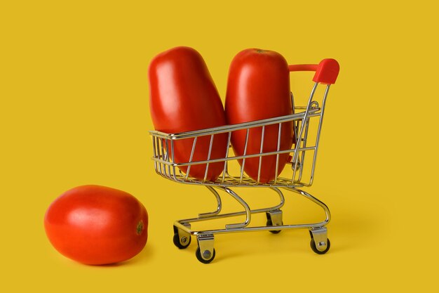 Mini shopping basket with tomatoes isolated on yellow background. retail. sales concept.