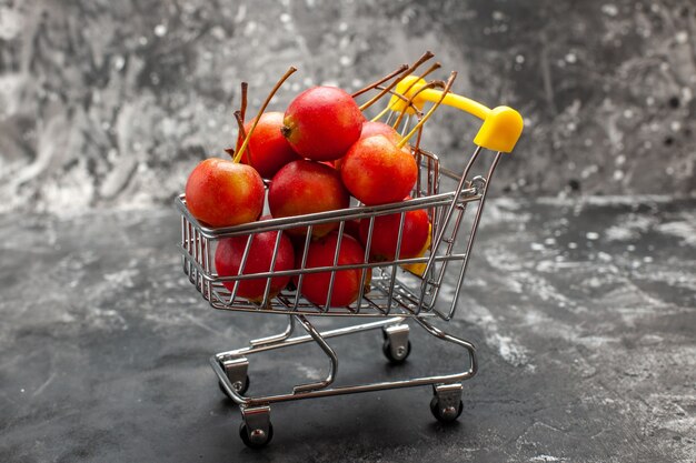 Mini shopping chart with red cherries on gray background
