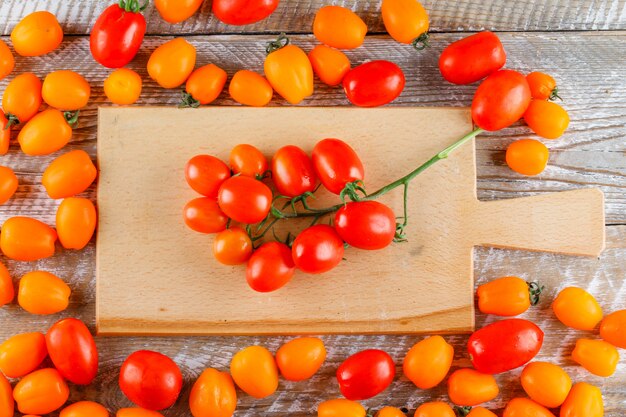 Mini tomatoes on wooden and cutting board, flat lay.