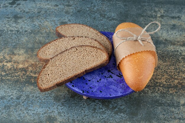 Mini white bread with slices of fresh brown bread on blue plate