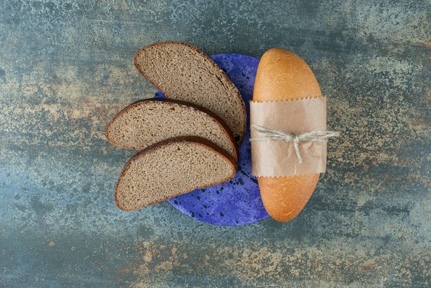 Mini white bread with slices of fresh brown bread on blue plate