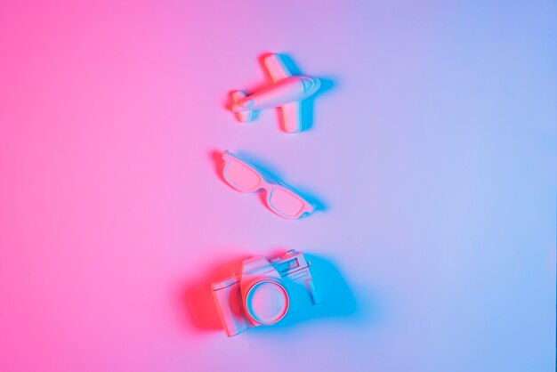 Miniature airplane; spectacle and retro camera over pink backdrop