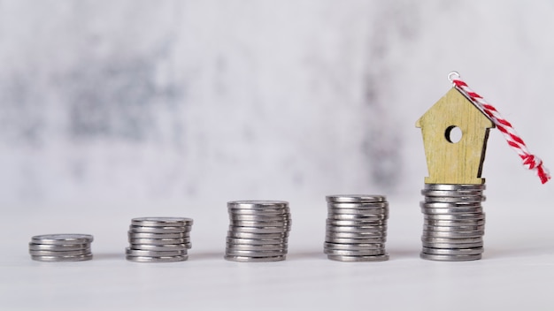 Miniature birdhouse ornament over the increasing stacked of silver coins