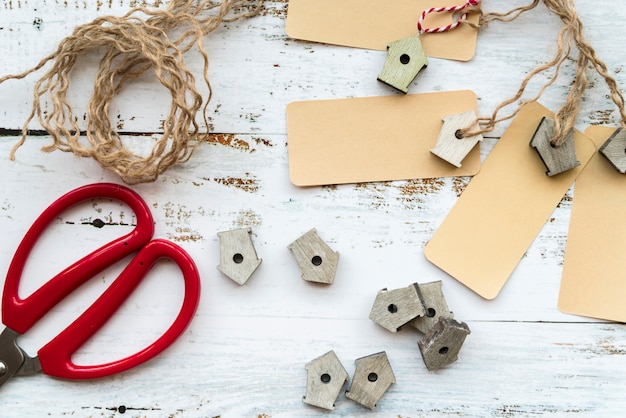 Free photo miniature birdhouses; tags; string and scissors on white desk