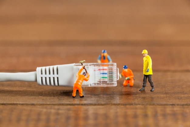 Miniature engineer and workers working with lan cable