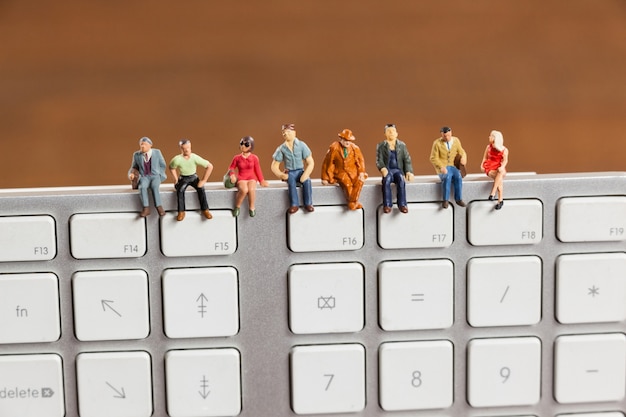 Free photo miniature people sitting on top of keyboard