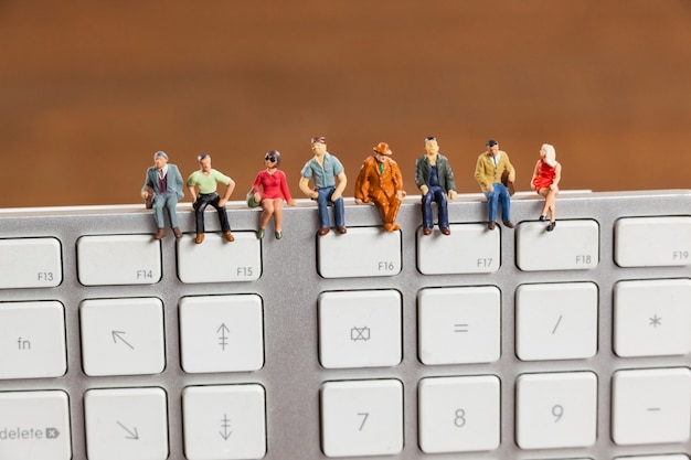 Miniature people sitting on top of keyboard