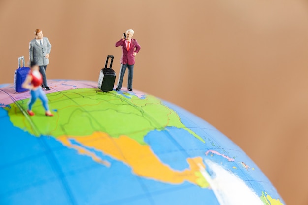 Miniature people travelling on globe