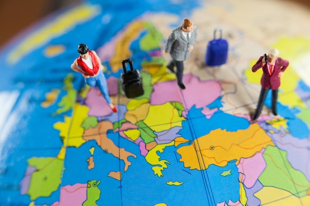 Miniature people travelling on globe