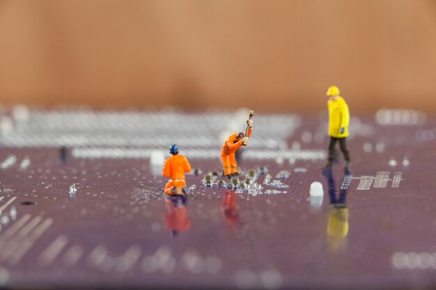 Miniature workers working on chip of motherboard