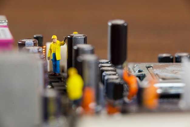 Miniature workers working on chip of motherboard