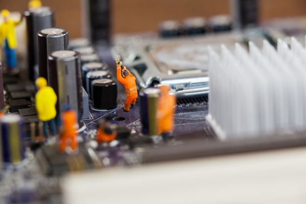 Free photo miniature workers working on chip of motherboard