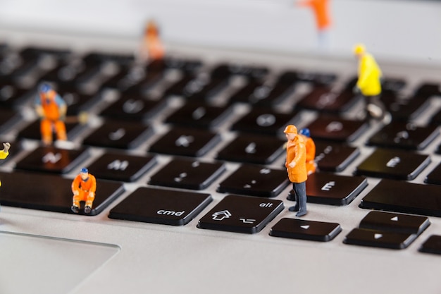 Miniature workmen repairing a laptop keyboard