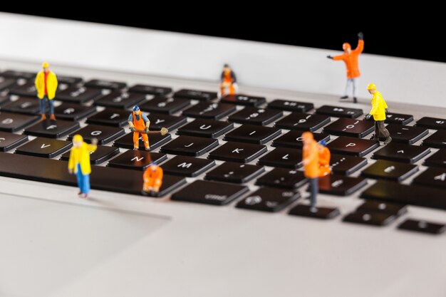 Miniature workmen repairing a laptop keyboard