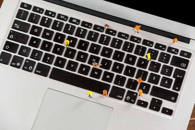 Miniature workmen repairing a laptop keyboard