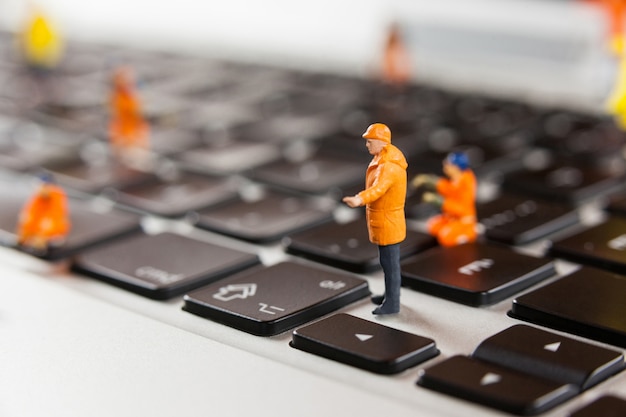 Free photo miniature workmen repairing a laptop keyboard