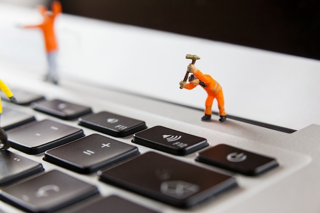 Free photo miniature workmen repairing a laptop keyboard