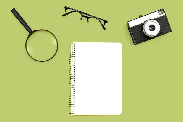 Free photo minimal background with blank paper camera glasses and magnifier flat lay