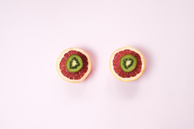 Минимальный фруктовый фон Вид сверху на нарезанные цитрусовые грейпфрут и киви на розовом столе Вид сверху на плоскую планировку