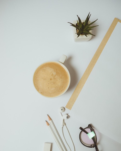 Spazio di lavoro minimo della scrivania con penna per appunti tazza da caffè su sfondo bianco vista dall'alto piatta