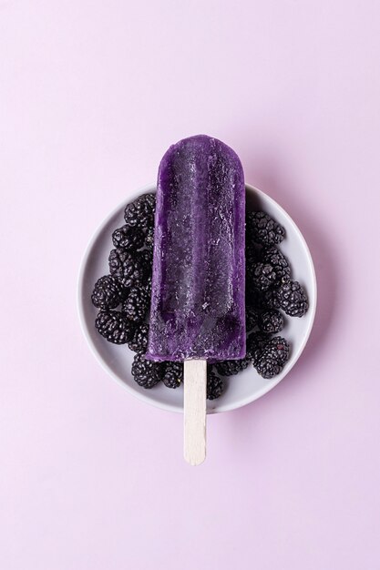 Minimalist blueberry ice cream on stick surrounded by berries