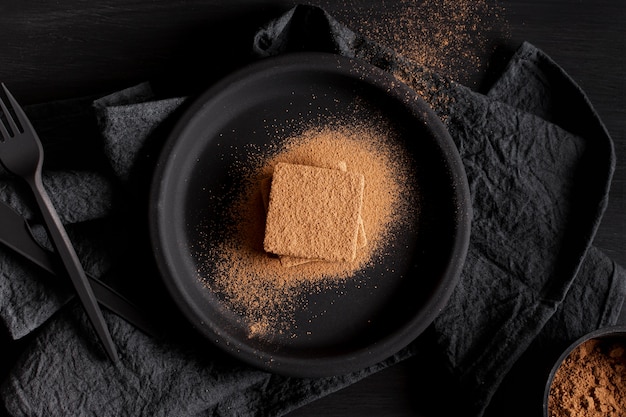 Minimalist chocolate powder on black plate and napkins