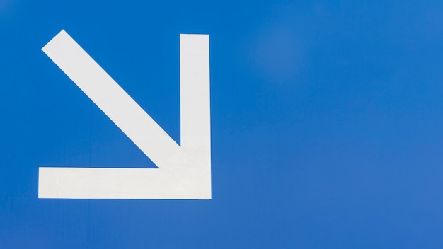 minimalist white downstairs arrow on blue background