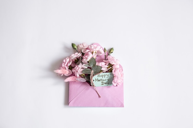 母の日のミニマルな構成。コピースペース内に花が飾られた装飾的な封筒。