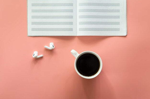 Minimalistic pink background with a cup of coffee notepad flat lay