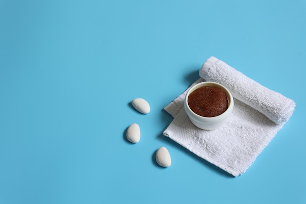 Free photo minimalistic spa composition with natural scrub and towel on blue background, copy space, face and body skin care concept.