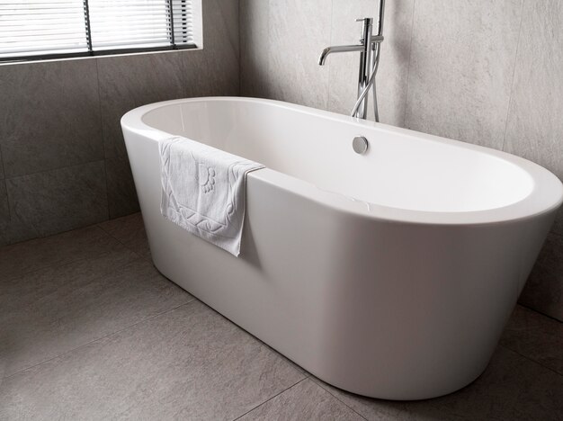 Free photo minimalistic white bathtub with a towel on it