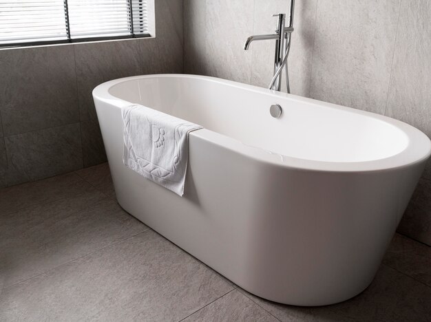 Minimalistic white bathtub with a towel on it