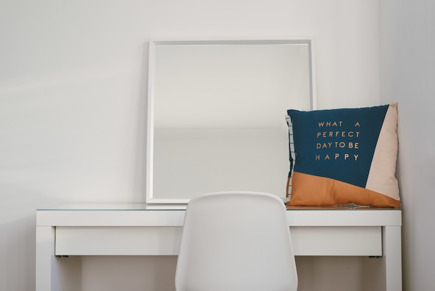 Mirror and a cushion on a white table with a chair in front