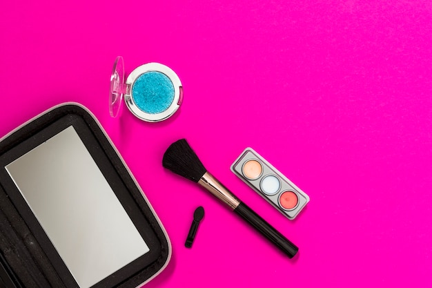 Free photo mirror; makeup brush and eyeshadow on pink background