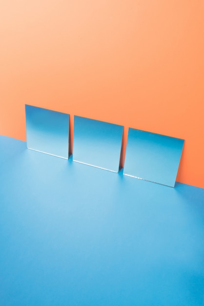 Specchi sulla tavola blu isolata sull'arancia
