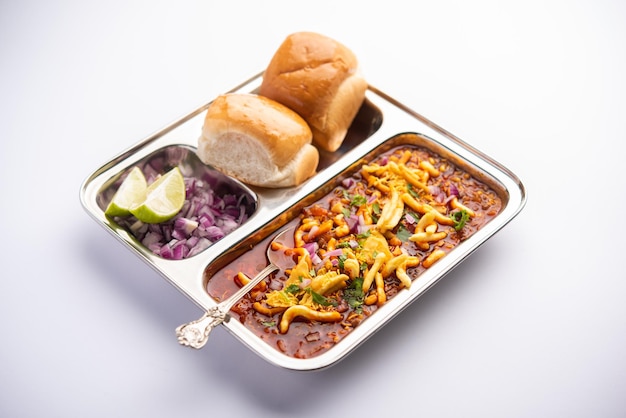 Misal pav is a popular maharashtrian street food of usal, sprouts curry, topped with onions, tomatoes, farsan and chutney Premium Photo