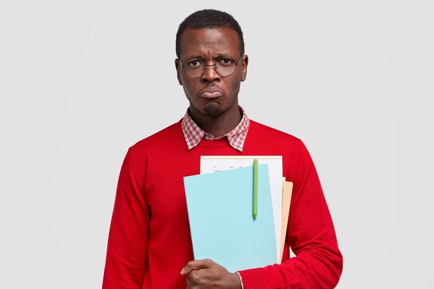 Miserable displeased offended black male college student, wants to cry from negative emotions, carries textbook with pen, feels fed up of studying