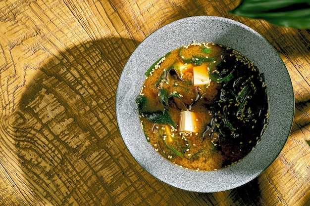 Суп мисо с тофу и грибами шиитаке в миске на деревянном фоне