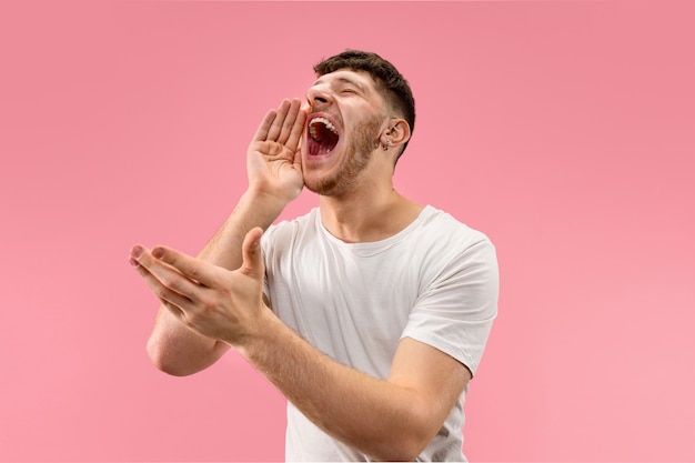 Free photo do not miss. young casual man shouting. shout. crying emotional man screaming on pink studio background. male half-length portrait. human emotions, facial expression concept. trendy colors