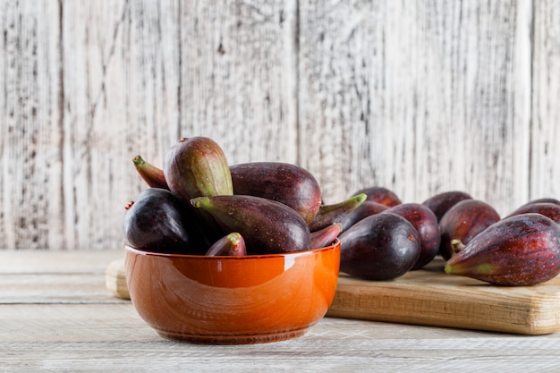 Mission figs in a bowl and on cutting board on a light wooden table. side view. free space for your text