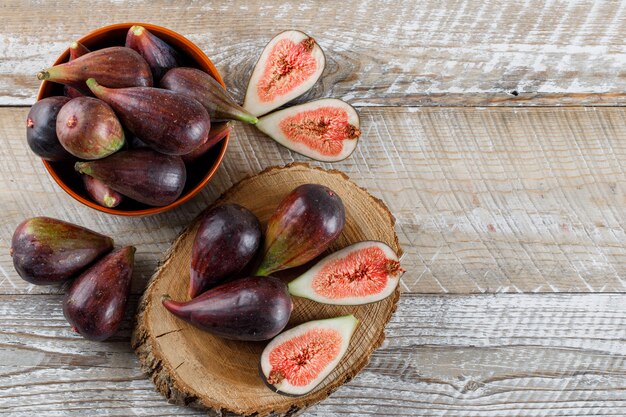 Mission figs and halves in a bowl and on a wood slice flat lay on a light wooden table space for text