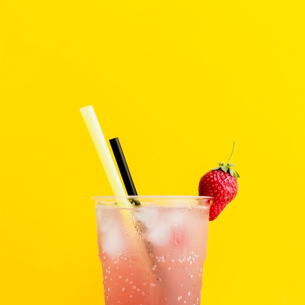 Misted glass of cocktail with strawberry and straws