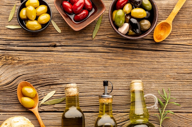 Foto gratuita mix di olive in ciotole e bottiglie di olio