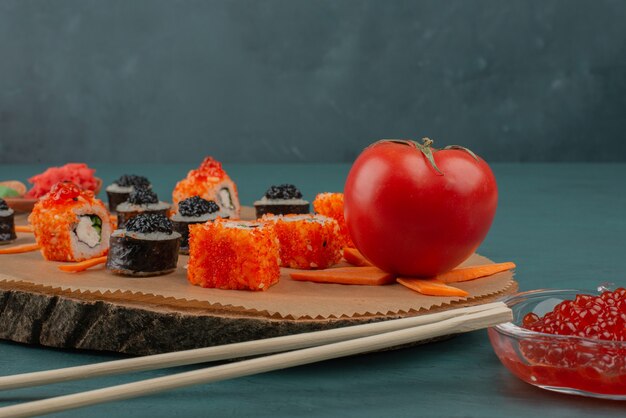 Mix sushi and red caviar on blue surface.