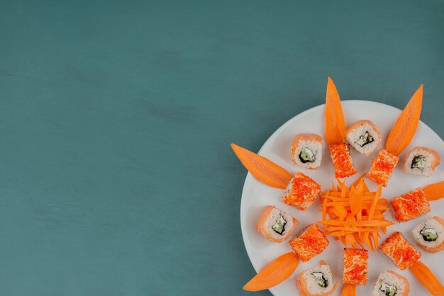 Mix sushi with carrot slices on wooden board.